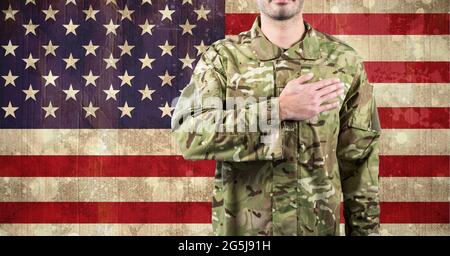 Zusammensetzung des Mittelteils des männlichen Soldaten mit Hand auf Herz, gegen die amerikanische Flagge Stockfoto