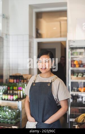 Porträt einer lächelnden Besitzerin mit Händen in den Taschen im Laden Stockfoto