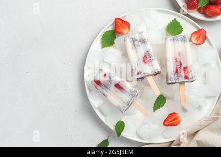 Drei Eiscremes auf einem Teller mit Eis auf hellem Hintergrund. Stockfoto