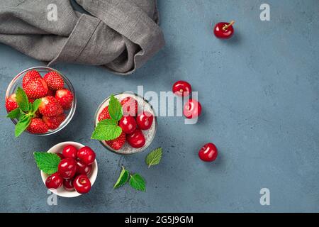 Milchdessert mit Chiasamen, frischen Kirschen, Erdbeeren und Minze auf blauem Hintergrund. Stockfoto