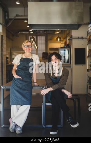 Weibliche Besitzerin, die neben einem männlichen Mitarbeiter im Geschäft steht Stockfoto