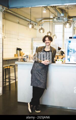 Porträt eines lächelnden männlichen Besitzers mit zusammengeklemmten Händen, die im Laden stehen Stockfoto