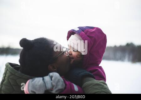 Liebevolle Mutter küsst Tochter auf den Mund Stockfoto