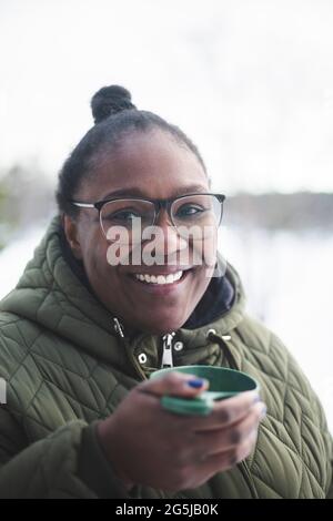 Porträt einer lächelnden Frau mittleren Erwachsenen, die während des Winters einen Drink hält Stockfoto