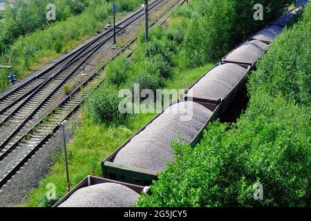 Mit Kohle beladene Güterwagen der Eisenbahn. Güterzug, der Kohle, Holz, Brennstoff transportiert. Draufsicht Stockfoto