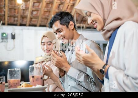 Nahaufnahme einer Gruppe junger asiatischer Menschen, die gemeinsam beten, bevor sie ihr Fasten brechen Stockfoto