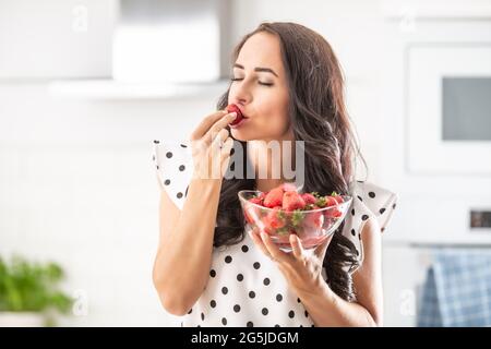 Die Frau verwöhnt Sie mit einem Geschmack einer frischen Erdbeerschale voller frisch gepflückter Ernte. Stockfoto