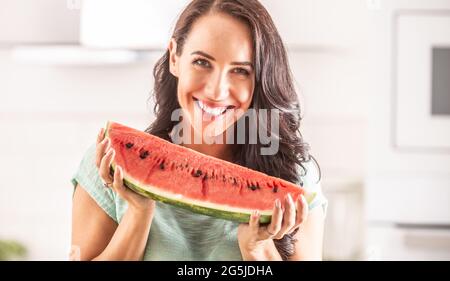 Frau hält ein großes Stück Wassermelone und lächelt. Stockfoto