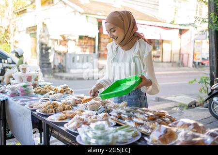 Ein schönes Mädchen, das einen Hijab mit einer Zange trägt, wählt Snacks aus, die gekauft werden sollen Stockfoto