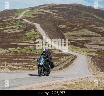 Ein Biker- und Pillionpassagier verhandelt die beliebte Route des schottischen Bergs A939 zwischen Tomintouil in Strathspey und Strathdon in Donside Aberdeen. Stockfoto