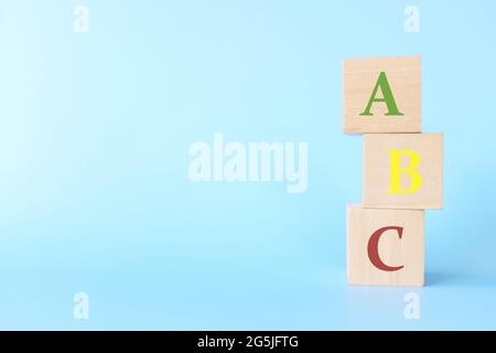 Bunte ABC-Buchstaben auf Holzblöcken auf blauem Hintergrund mit Kopierraum. Beginn des Kindes oder des Kindes, das Alphabet-Konzept zu erlernen. Stockfoto