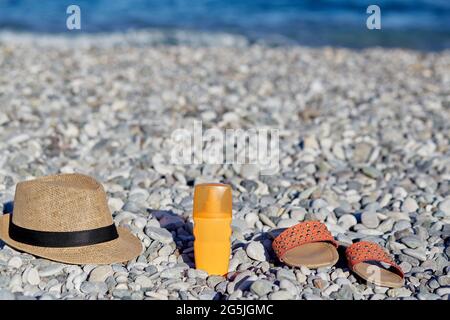 Sonnencreme, Sommerschuhe und Hut am Strand. Konzept von Spa, Beauty, Kosmetik, Sonnencreme und Feuchtigkeitscreme. Sommerkonzept. Hochwertige p Stockfoto