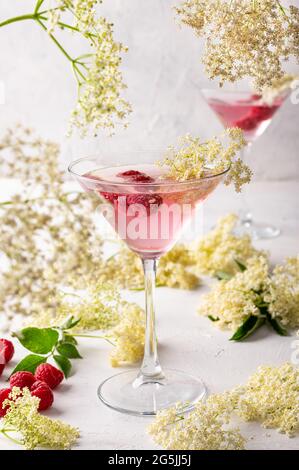 Gin und Tonic mit Holunderblüten erfrischenden Sommer rosa Cocktail garniert mit Himbeeren Stockfoto