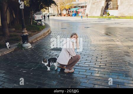 Porträt einer jungen Frau, die mit einer Katze in der Stadt spielt Straße Stockfoto