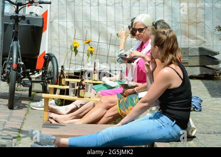 Freiburg im Breisgau, 26. Juni 2021: Vier Besucher nutzen das »Bächle« in der Herrenstraße, um sich die Füße zu kühlen. Stockfoto