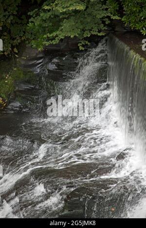 Wasser, das über einen künstlichen Steinwasserfall oder Wehr fließt, wird vom Aberdulais Waterwheel, Neath, Wales, abgeleitet Stockfoto