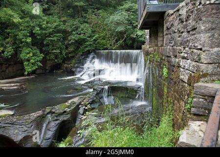 Wasser, das über einen künstlichen Steinwasserfall oder Wehr fließt, wird vom Aberdulais Waterwheel, Neath, Wales, abgeleitet Stockfoto