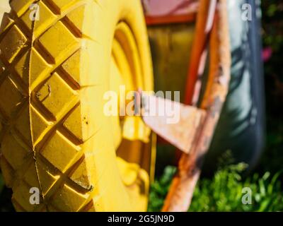 Selektiver Fokus auf ein gelbes Rad eines Gartenwagens an einem sonnigen Sommertag. Unscharfer Hintergrund. Stockfoto