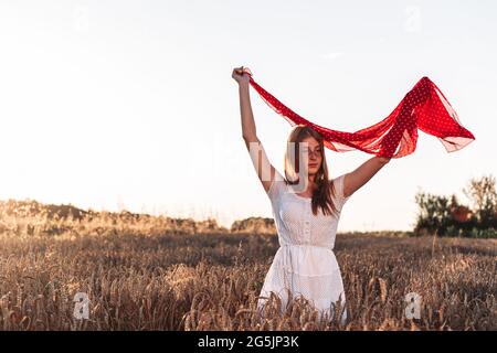 Im Freien Foto von jungen, Ingwer Mädchen in weißem Kleid hält einen roten Schal flattern in der Luft. Stockfoto