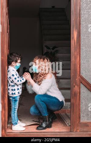 Mama und ihr Kleinkind Sohn trägt Gesichtsmasken immer bereit Zum Ausgehen Stockfoto