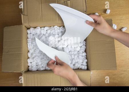 Zerbrochene Platte in beschädigtem Karton Draufsicht, beschädigter Hauslieferungs-Auspackkarton Stockfoto