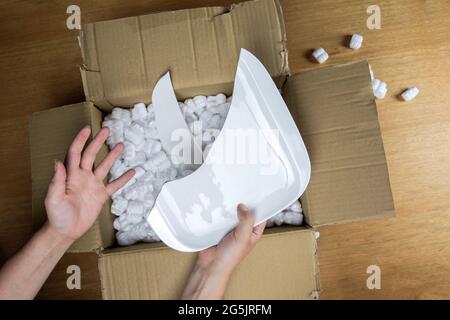 Zerbrochene Platte in beschädigtem Karton Draufsicht, beschädigter Hauslieferungs-Auspackkarton Stockfoto