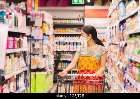 Frau in Schutzmaske einkaufen im Supermarkt während Coronavirus Quarantäne. Stockfoto