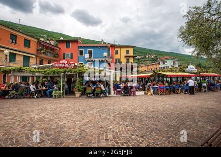 Restaurants und Pizzeria mit vielen Leuten, die im kleinen Dorf Castelletto di Brenzone am Gardasee zu Mittag essen. Verona, Venetien, Italien, Europa. Stockfoto