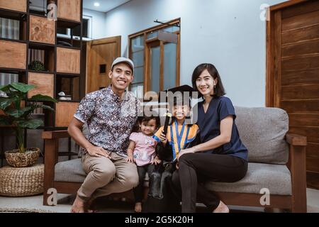 Glückliche asiatische Familie Absolvent zu Hause. Grundschule Schüler zu Hause feiern Stockfoto