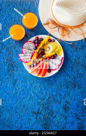 Tropische Früchte Frühstück im Urlaub. Obst mit frischem Saft und Hut, Blick von oben Stockfoto