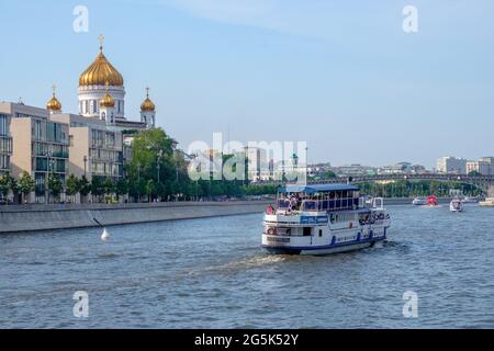 Moskau. Russland. 26. Juni 2021. Blick auf ein Vergnügungsboot, das entlang des Flusses Moskau segelt, vor dem Hintergrund der goldenen Kuppeln der Kathedrale von Stockfoto