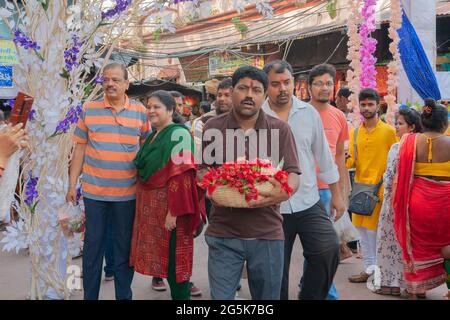 Kolkata, Westbengalen, Indien - 15. April 2019 : junger Mann, der Hibiskusblüten, Idole der Göttin Laxmi und Lord Ganesh für Anbetung in einem Eimer trägt. Stockfoto