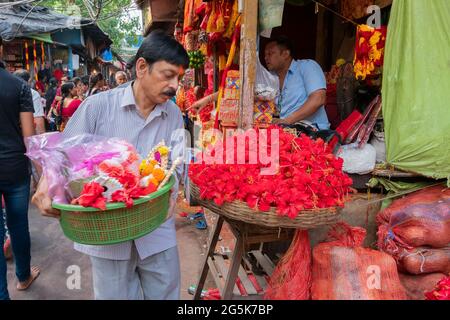 Kolkata, Westbengalen, Indien - 15. April 2019 : junger Mann, der Hibiskusblüten trägt, Idole der Göttin Laxmi und Lord Ganesh für Anbetung, in einem Plastik Stockfoto