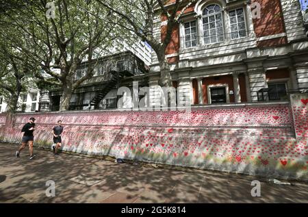 London, Großbritannien. Mai 2021. Jogger laufen entlang der National Covid Memorial Wall, am Südufer der Themse, gegenüber dem Houses of Parliament und erinnern daran, wie hart das letzte Jahr für viele war. Die Gedenkstätte entwickelt sich weiter – ursprünglich wurde für jeden der 150,000 Menschen, die während der Pandemie im Vereinigten Königreich ums Leben kamen, ein Herz gezogen. Die Öffentlichkeit fügt weiterhin Herzen und persönliche Botschaften hinzu, während das Denkmal zu einem festen Bestandteil des Lebens in London wird. Quelle: Martin Pope/SOPA Images/ZUMA Wire/Alamy Live News Stockfoto