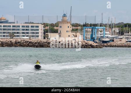 El Puerto de Santa Maria, Cadaz, Spanien - 16. Juni 2021: Glückliches kaukasisches Paar, das in der Nähe des Leuchtturms einen Jet-Ski fährt und den Eingang zum Marineinhaus anzeigt Stockfoto