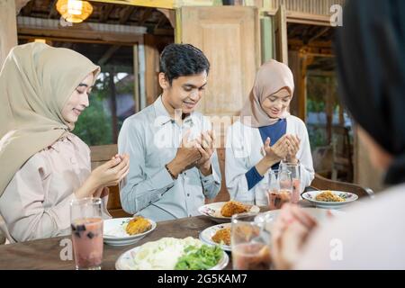 Ein muslimischer Mann und eine verschleierte Frau beten gemeinsam vor dem Essen Stockfoto