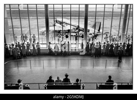 Besucher des Vintage-Flughafenterminals der 1940er Jahre beobachten die Boarding-Aktivitäten von DC3-Flugzeugen. Von der Aussichtsplattform auf dem städtischen Flughafen in Washington, D.C. aus gesehen] Jack Delano Fotograf [1941. Juli] Vereinigte Staaten--District of Columbia--Washington (D.C.) Das goldene Zeitalter des Fliegens. DC3 Silver Fleet Eastern Airlines Propellerflugzeuge vor dem Terminal, das Passagiere anfliegt. Stockfoto