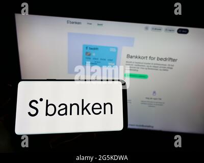 Person, die das Smartphone mit dem Logo der norwegischen Online-Bank Sbanken ASA auf dem Bildschirm vor der Website hält. Konzentrieren Sie sich auf die Telefonanzeige. Stockfoto