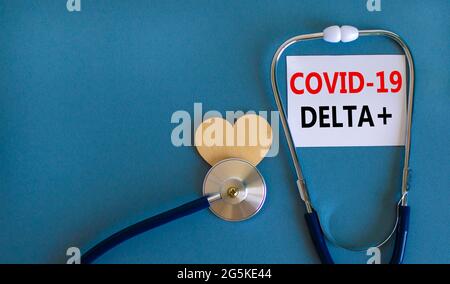 Neues Covid-19 Delta plus Variant Strain Symbol. Weiße Karte, Wörter Covid-19 Delta plus und Stethoskop, blauer Hintergrund. Holzherz. Medizinisch und covid Stockfoto