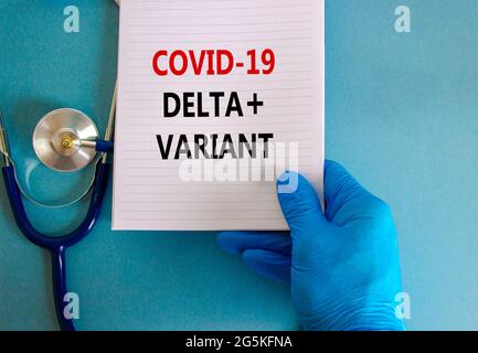 Covid-19 Delta plus Variant Dehnungssymbol. Ärztin Hand in blauem Handschuh, weiße Karte. Begriff „Covid-19 Delta plus Variante“. Stethoskop. Medizinisch, C Stockfoto