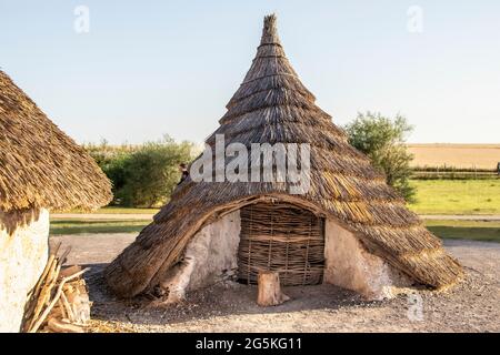 Nachgebaute, mit einem Dach ÜBERDACHTE NEOLITHISCHE HÄUSER wie die Menschen, die in alten Zeiten um Stonehenge herum gebaut und gelebt haben, lebten in der Salisbury Plain in Englan Stockfoto