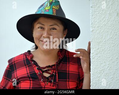 Die charmante junge mexikanische Yucatecan-Frau trägt einen handbemalten schwarzen Strohhut mit traditionellen Maya-Volksmotiven und lächelt für die Kamera. Stockfoto