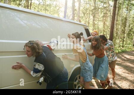 Gruppe von Menschen, die den Van während der Reise in die Natur zusammenschieben Stockfoto