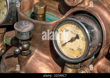 Nahaufnahme eines alten Manometers, eines Manometers in einem Kupfermaschinenkopf mit Fokus auf dem Maschinenkopf Stockfoto