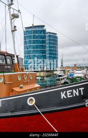 Die Quays Wohntürme mit dem Schlepper MT Kent, der im Vordergrund an der Chatham Maritime Marina, Kent, England, festgemacht ist. Stockfoto