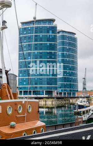 Die Quays Wohntürme mit dem Schlepper MT Kent, der im Vordergrund an der Chatham Maritime Marina, Kent, England, festgemacht ist. Stockfoto