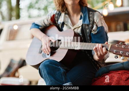 Nahaufnahme einer jungen Frau, die auf der Natur sitzt und Gitarre spielt Stockfoto