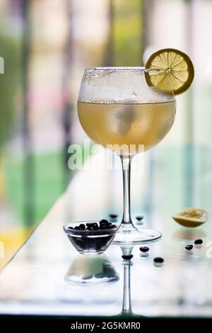 Kalter alkoholischer Cocktail cuba libre in einem Nebelglas mit Zitrone und Kaffeebohnen am Rand des Tisches in einem Café. Sommercafe Stockfoto