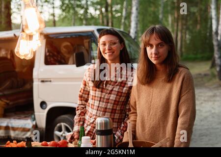 Porträt von jungen Frauen, die lächeln, während sie Zeit bei einem Picknick im Wald verbringen Stockfoto