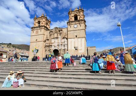 Indigene Frau in traditioneller Tracht sitzt auf der Treppe der Kathedrale, Catedral Basílica San Carlos Borromeo, Puno, Lake Titicaca, Peru, Sout Stockfoto